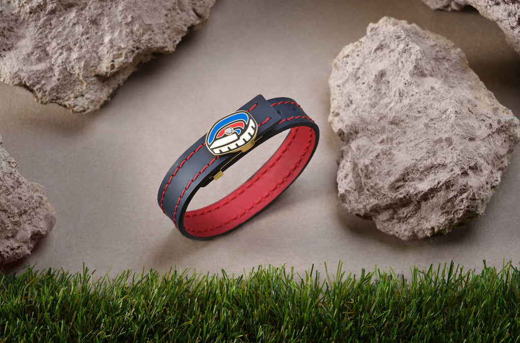 La icónica pulsera Spotify Camp Nou, bañada en oro y esmalte, con cuero genuino en un llamativo diseño bicolor, rodeada de césped y piedras que capturan la esencia del Spotify Camp Nou. El diamante en su centro resalta con destello único.